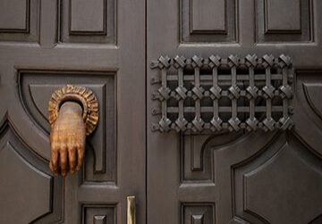 Ornate door with hand-shaped knocker.